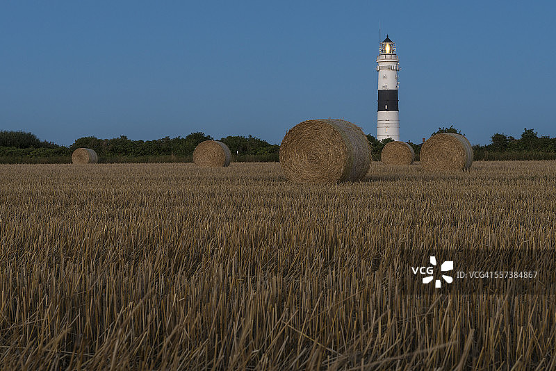 德国石勒苏益格-荷尔斯泰因州叙尔特岛，坎彭灯塔，有干草捆的 stubble field图片素材
