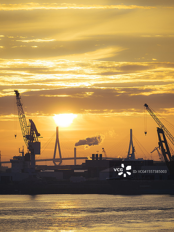 德国汉堡：日落时分港口起重机的轮廓，背景是科尔布兰特桥图片素材