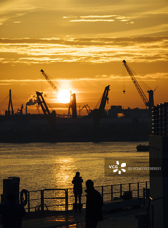 德国汉堡：日落时分港口起重机的轮廓，背景是科尔布兰特桥图片素材