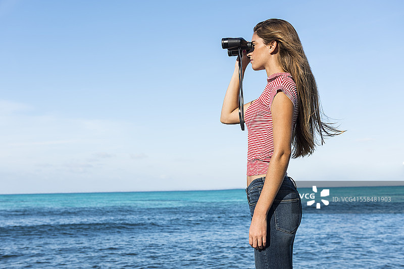 用双筒望远镜看地平线的女人图片素材