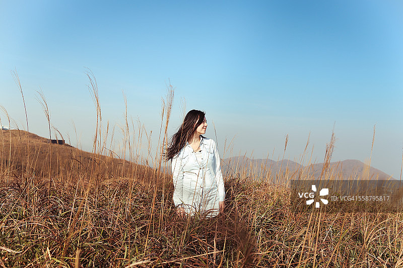 快乐的女孩站在胡须草地里图片素材