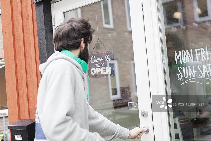 男子打开咖啡馆门的侧视图图片素材