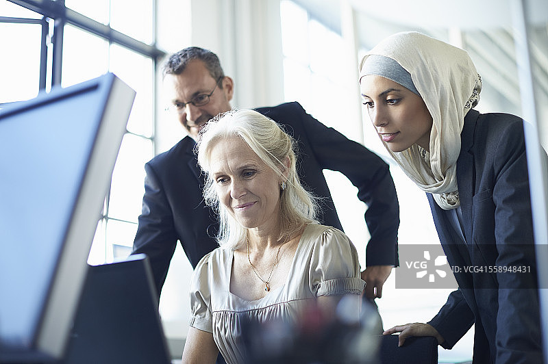 在办公桌前看个人电脑的商务团队图片素材