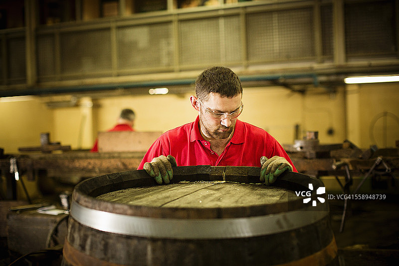 在酿酒厂用威士忌酒桶工作的男性制桶匠图片素材