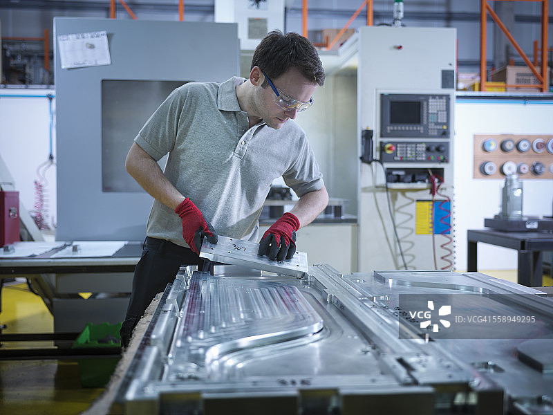 工人在塑料厂检查模具部件图片素材