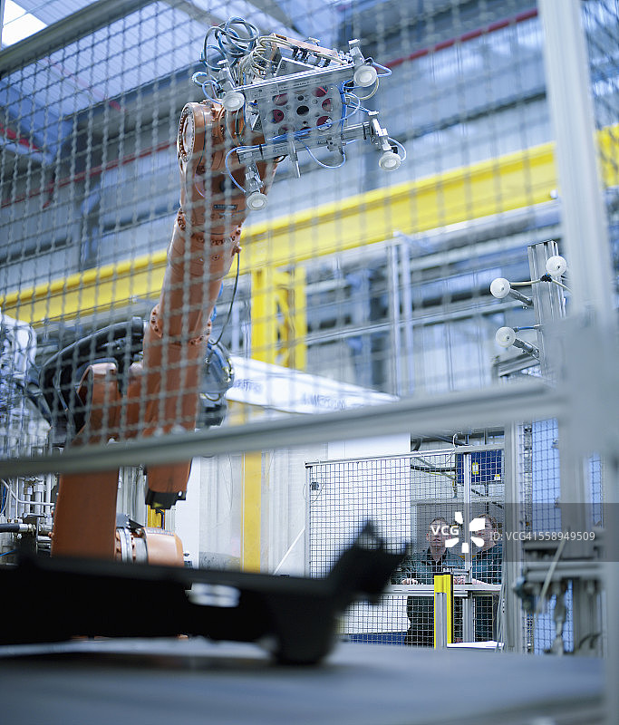 工人在工厂观看机器人执行任务图片素材