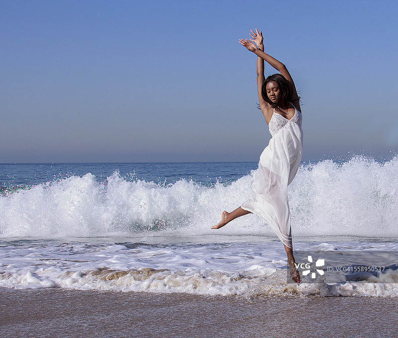 年轻女舞蹈演员在海浪中跃起图片素材