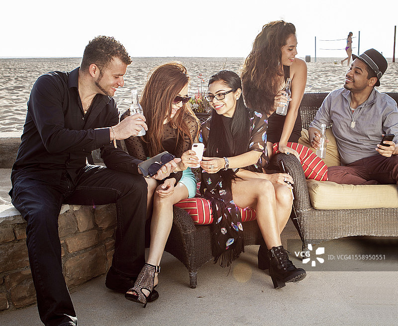 一群朋友在海滩酒吧聊天看手机图片素材