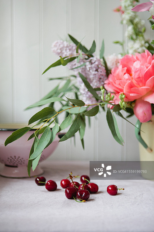 桌子上的樱桃和一束鲜花图片素材