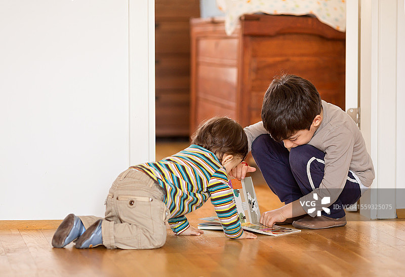 兄妹在家中地板上读书图片素材