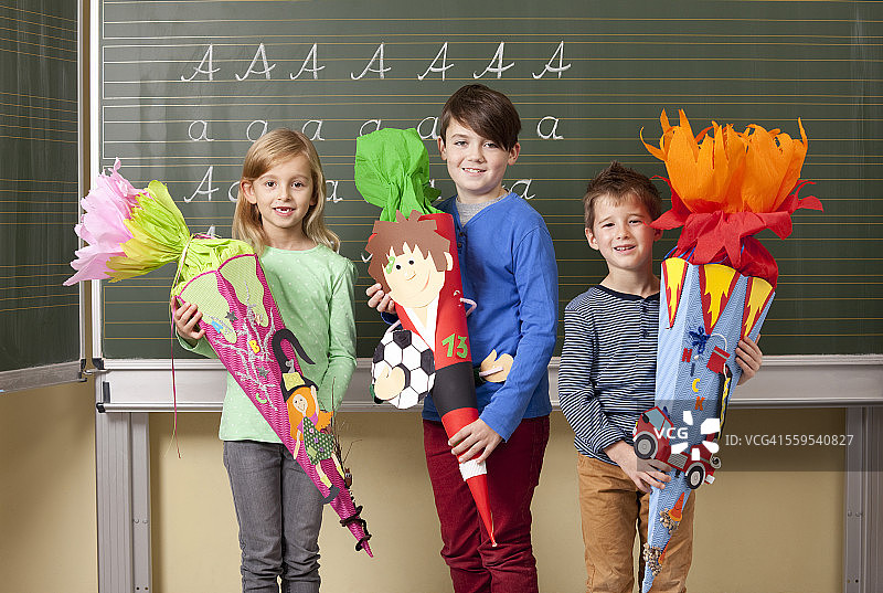 快乐的小学生们在黑板前拿着学校锥图片素材