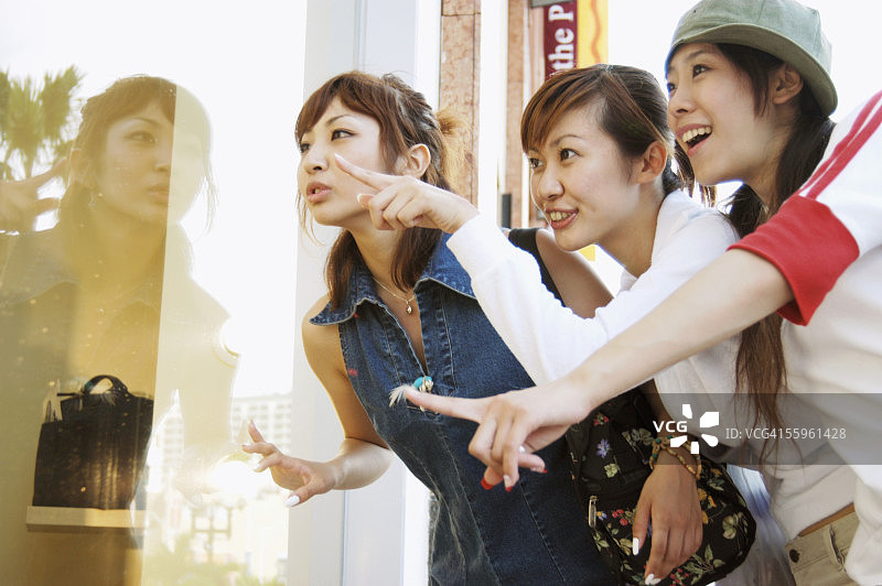 在商店橱窗前观看的年轻女性图片素材