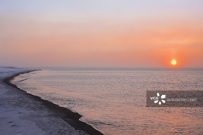 夕阳穿过风吹的雪，在美国阿拉斯加州巴罗郊外的博福特海沿岸形成幻日图片素材