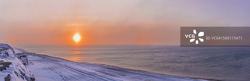 夕阳穿过风吹的雪，在美国阿拉斯加州巴罗郊外的博福特海沿岸形成幻日图片素材