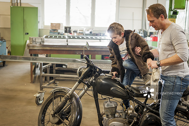 父子共同维护复古轻便摩托车图片素材