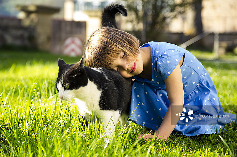 草地上抱着猫的小女孩图片素材