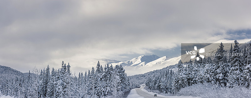 冬季暴风雪后，楚加奇国家森林公园特纳根隘口上方的克奈山脉，苏厄德高速公路上的云层消散，树木上覆盖着新鲜的雪，清晨的阳光图片素材