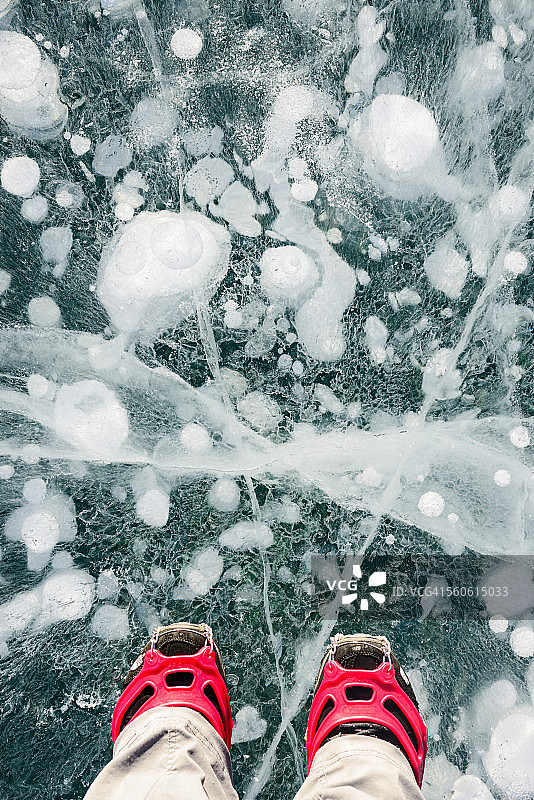 踩在充满气泡的蓝色冰面上的双脚图片素材