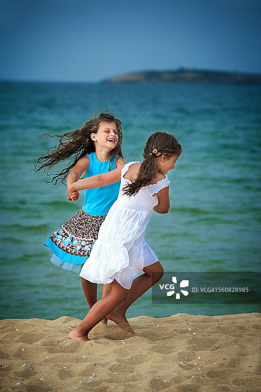 在海滩上牵手玩耍的两个小女孩图片素材