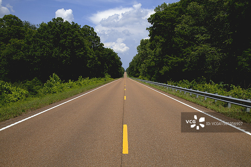 树木成行的道路，远处是云图片素材