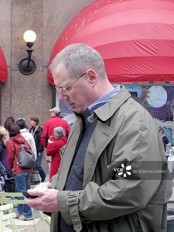 穿雨衣发短信的男人图片素材