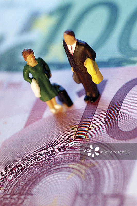 站在欧元纸币上的玩具商人和女商人图片素材