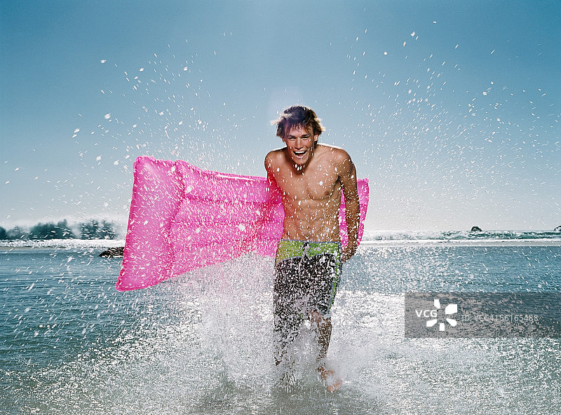 在海里拿着充气玩具的年轻男人图片素材