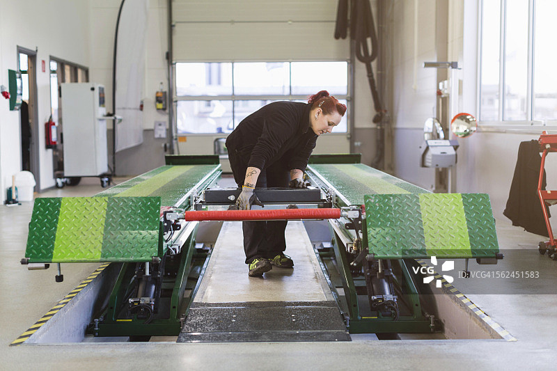 女修理工在汽车修理店使用液压升降机图片素材