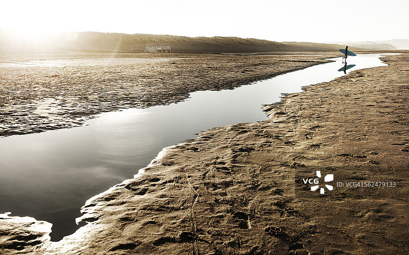 冲浪者在海滩上穿越洪水时的倒影图片素材