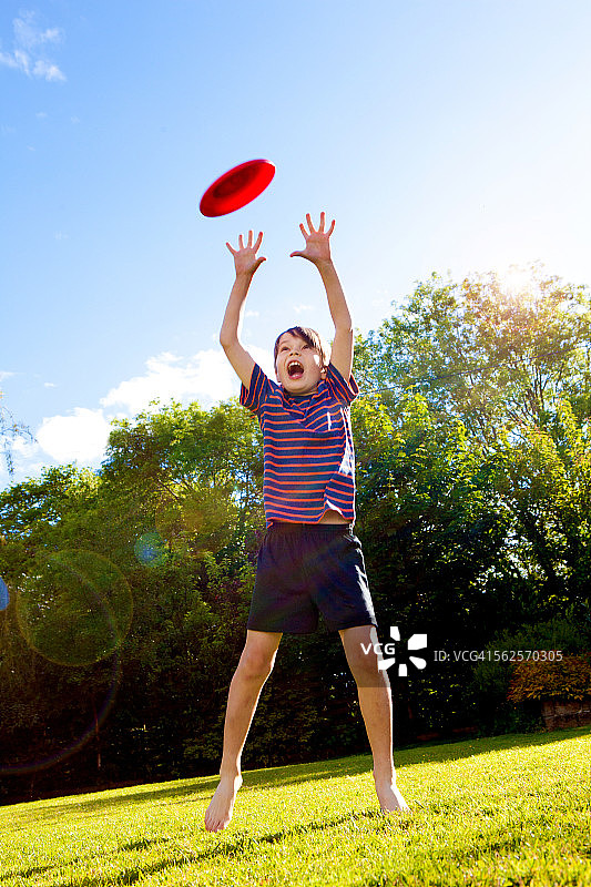 在花园里跳起来接飞盘的小男孩图片素材