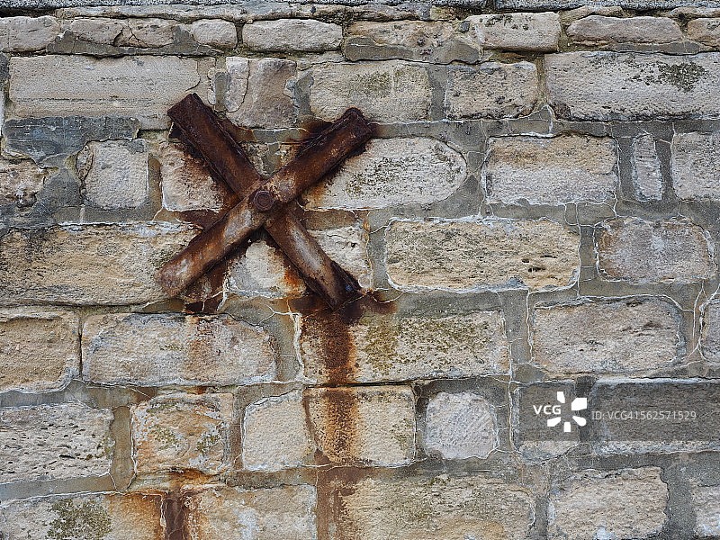 砖墙上的生锈铁十字架图片素材