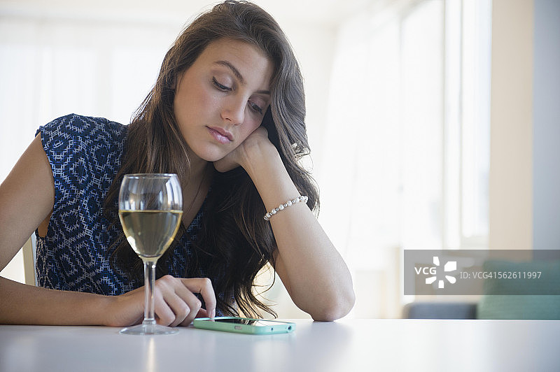 一边喝着红酒一边发短信的悲伤女人图片素材