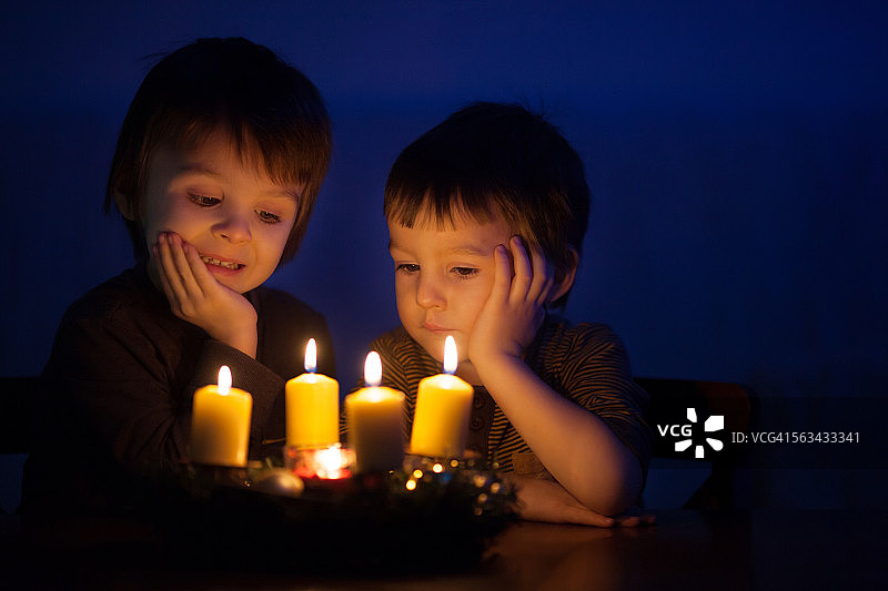 两个小男孩看着燃烧的蜡烛图片素材