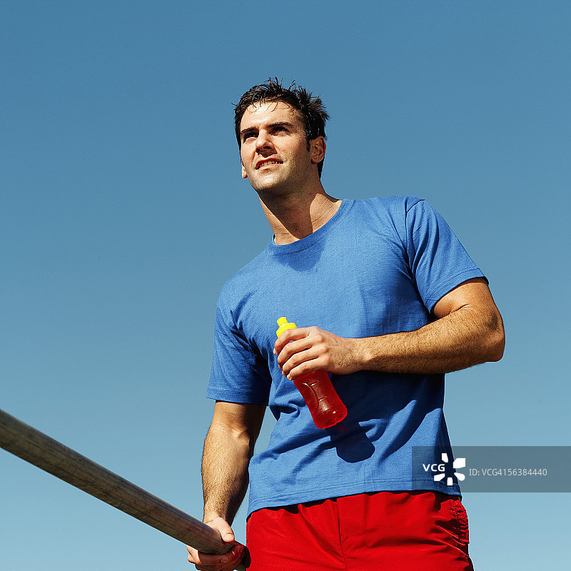 仰视拿着运动饮料瓶的年轻男人图片素材