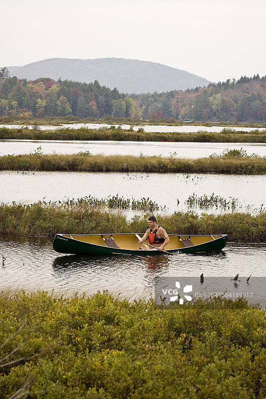 年轻男人在位于美国纽约州塔珀湖附近的水道上划独木舟图片素材