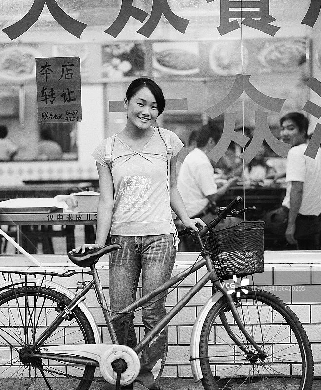 站在餐厅前、和自行车在一起的少女写真图片素材
