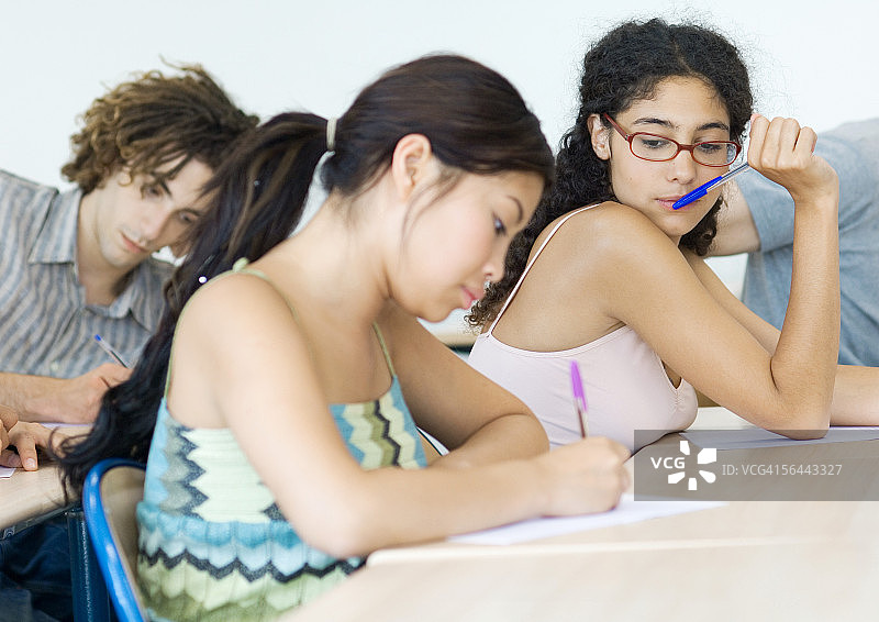 学生们在课堂考试，一人偷看试卷图片素材