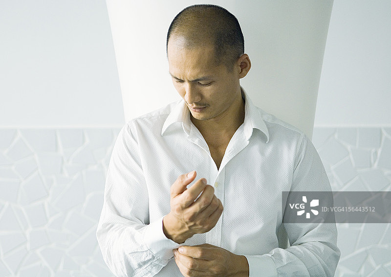 穿着白色衬衫的男子在扣袖口图片素材