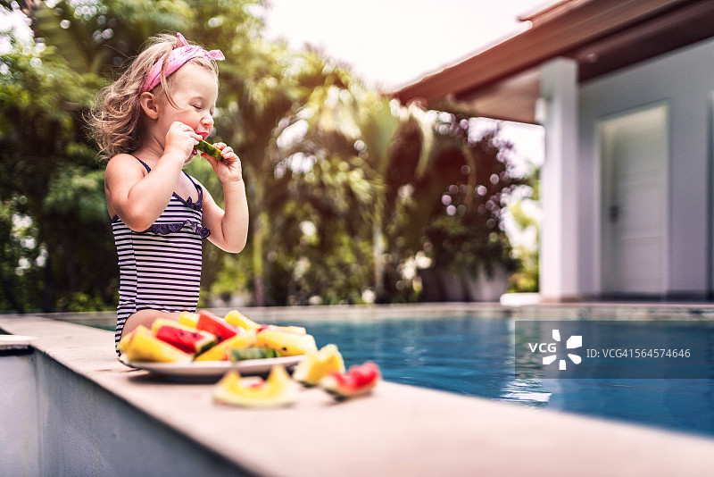 可爱女孩坐在泳池边吃西瓜图片素材
