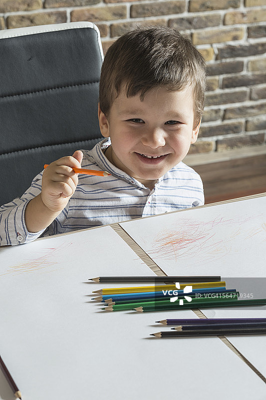 在家里桌旁画画的快乐男孩肖像图片素材