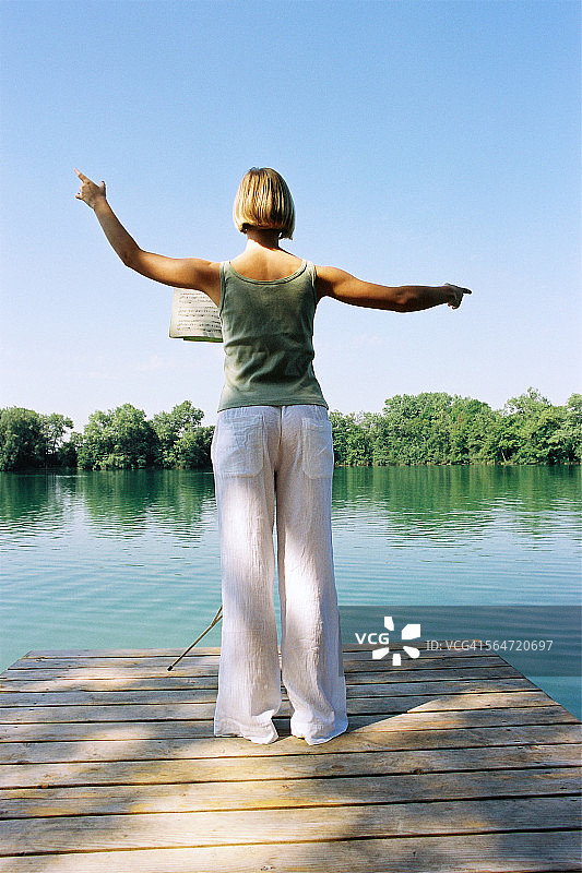 年轻女子在湖边指挥图片素材