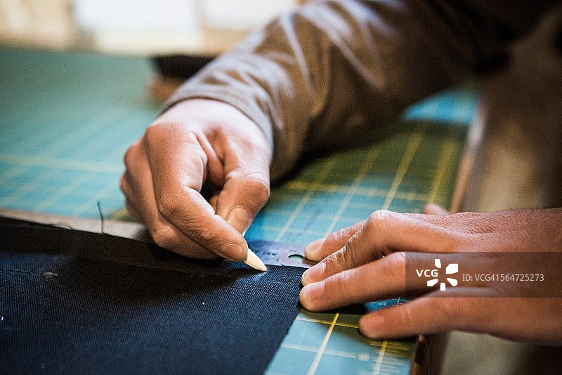 裁缝在工作台上用粉笔标记布料的手图片素材