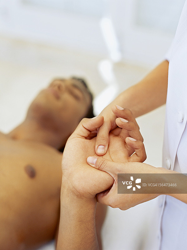 年轻男人接受按摩师的手部按摩图片素材
