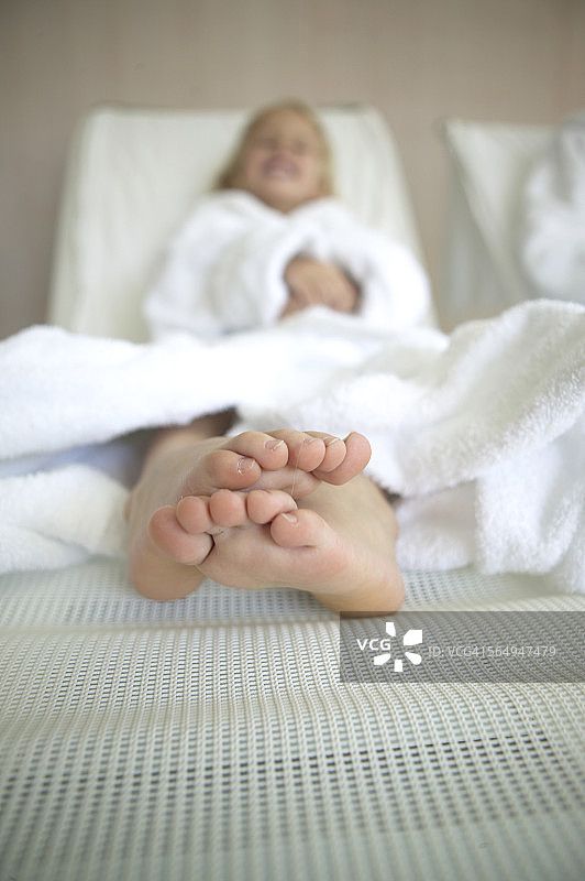 赤脚女孩躺在酒店水疗中心的沙发上图片素材