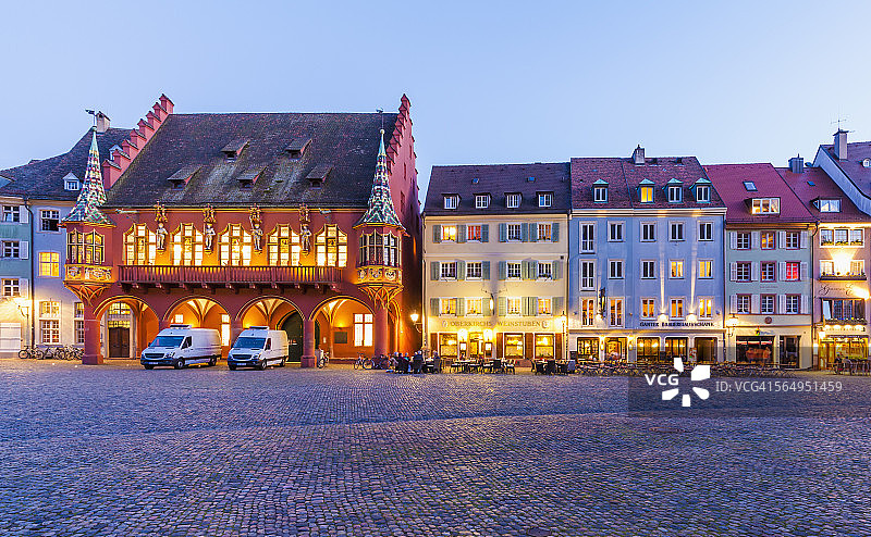 德国巴登-符腾堡州弗莱堡老城区明斯特广场历史悠久的百货商店和餐厅蓝色时刻图片素材