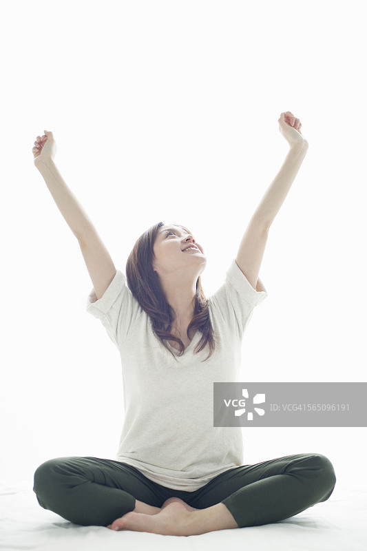 在床上微笑伸展的年轻女人图片素材