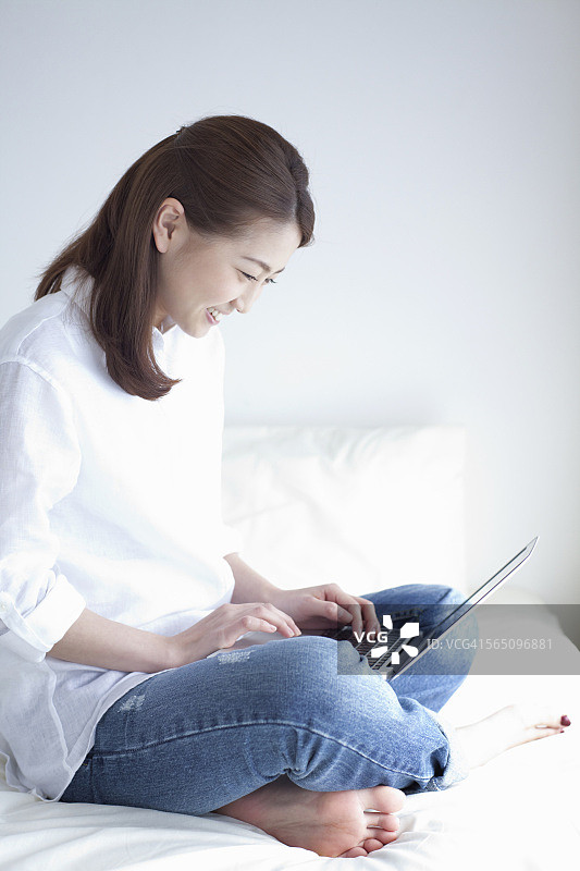 女人坐在床上用笔记本电脑图片素材