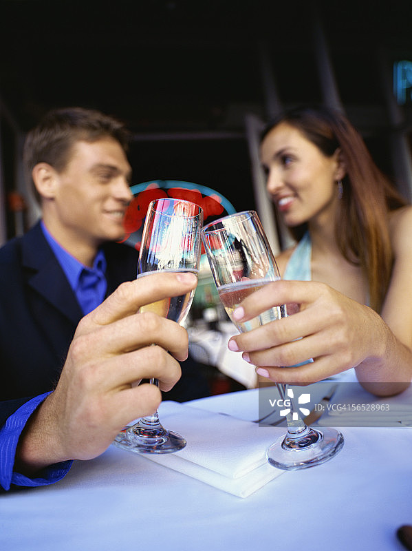 年轻情侣坐在餐厅里敬酒图片素材