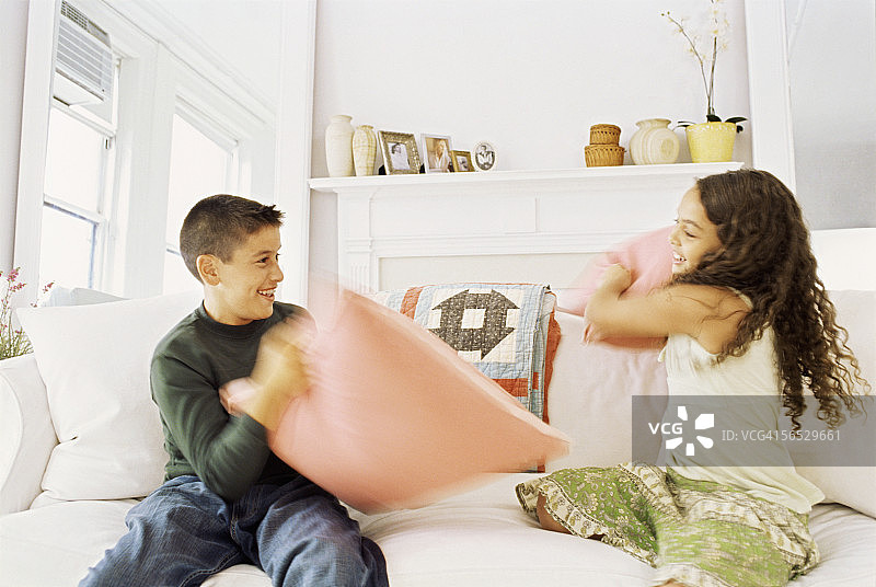 哥哥和妹妹枕头大战的侧面照图片素材