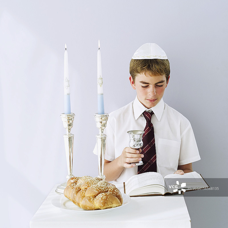 犹太男孩手拿圣餐杯阅读塔木德经图片素材